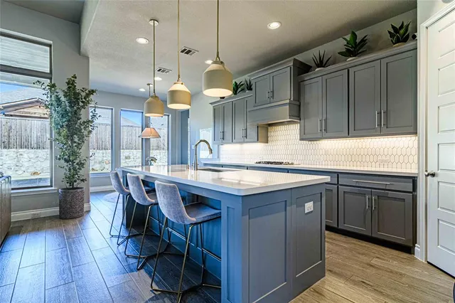 a kitchen with kitchen island granite countertop a sink a counter space appliances and cabinets