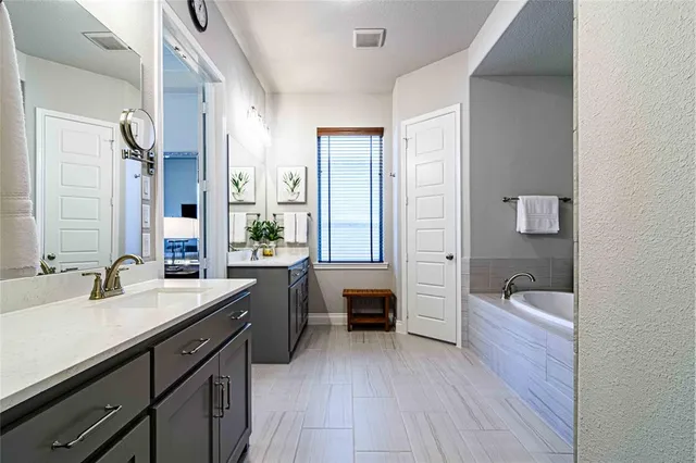 a spacious bathroom with a bathtub double sink and a large mirror