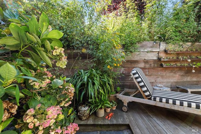 a view of a patio with table and chairs and potted plants with wooden floor and fence
