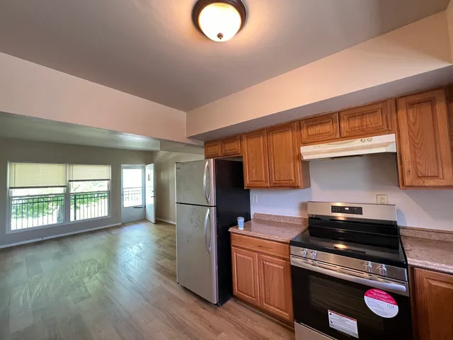 a kitchen with granite countertop a stove a sink dishwasher and a refrigerator with wooden floor