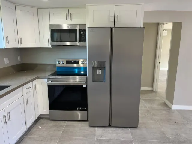 a kitchen with stainless steel appliances granite countertop a refrigerator and a stove top oven