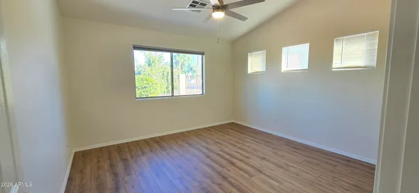 an empty room with wooden floor and windows