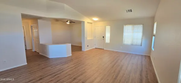 a view of an empty room with wooden floor and a bathroom