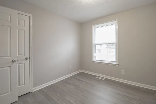 an empty room with wooden floor and windows