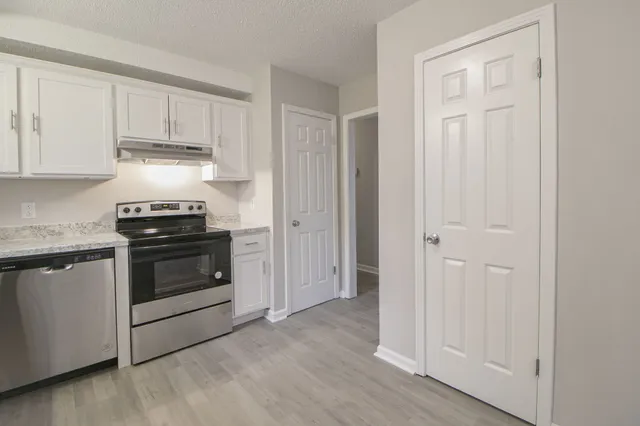 a kitchen with granite countertop white cabinets and stainless steel appliances