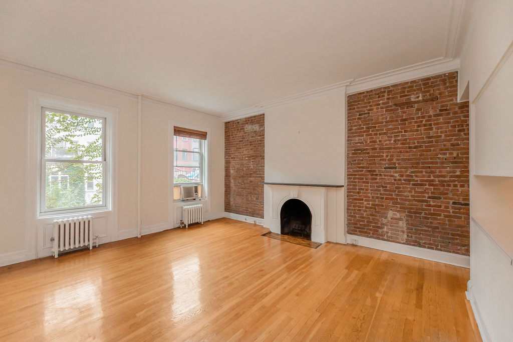 a view of empty room with fireplace and wooden floor