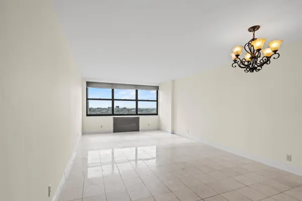 an empty room with windows and chandelier fan