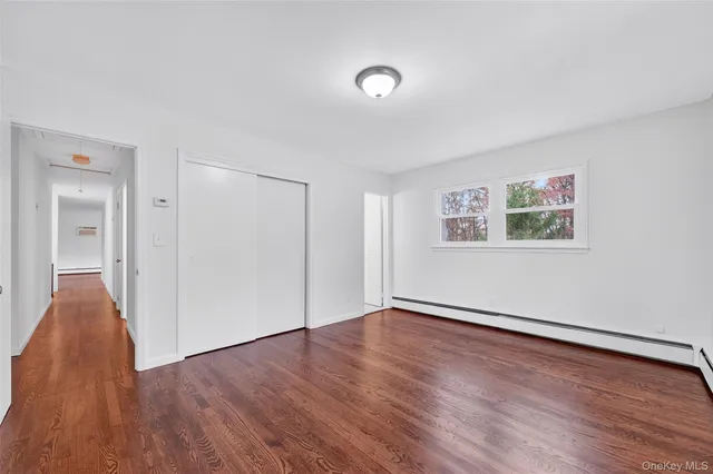 an empty room with wooden floor fireplace and windows