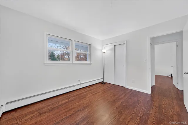 an empty room with wooden floor fireplace and windows
