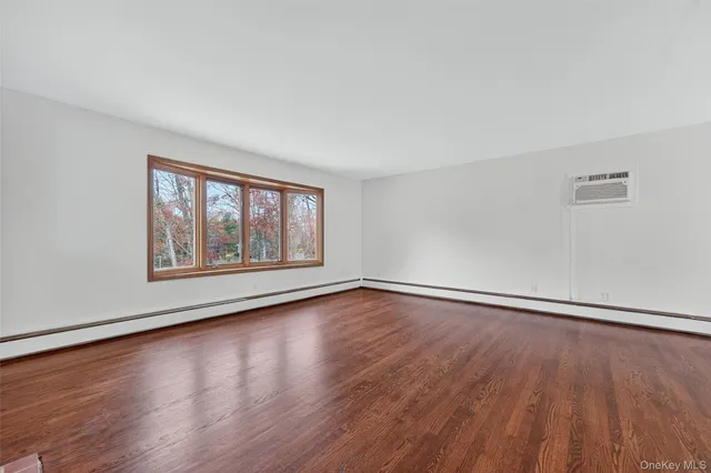 a view of an empty room with wooden floor ceiling fan