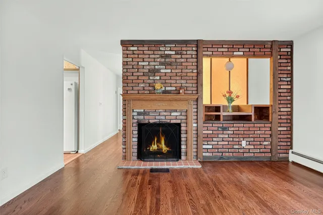 a view of a kitchen and an empty room with wooden floor