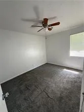 an empty room with a ceiling fan and window