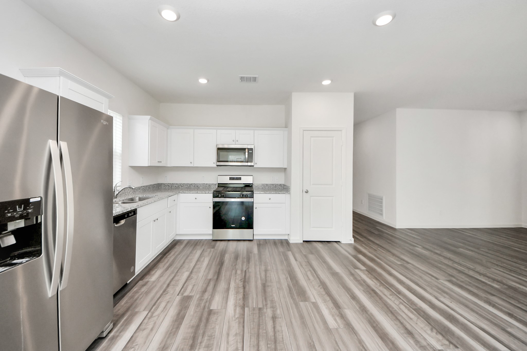 10306 Tuscan Valley Drive Rosharon, TX 77583 - Photo 4 of 48 a kitchen with wooden floors stainless steel appliances and white cabinets