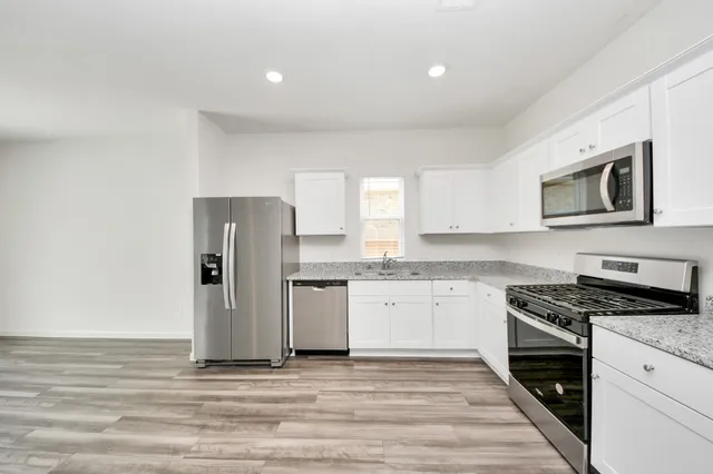 a kitchen with granite countertop a refrigerator stove top oven and sink