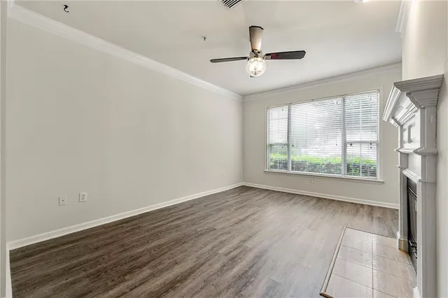 an empty room with wooden floor chandelier fan and windows