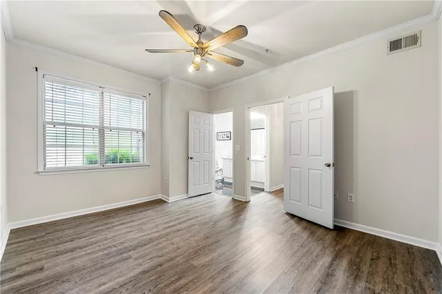 an empty room with wooden floor and ceiling fan