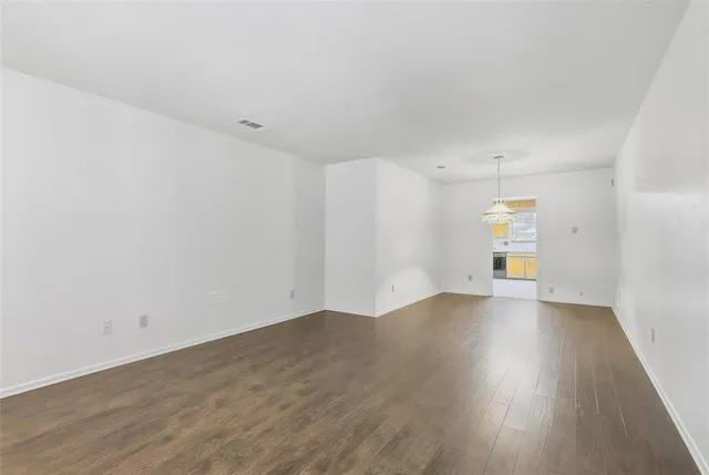 a view of an empty room with window and wooden floor
