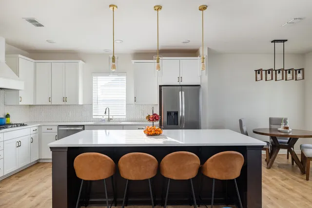 a kitchen with a dining table chairs and white appliances