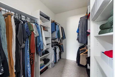 a view of walk in closet with clothes and shoes