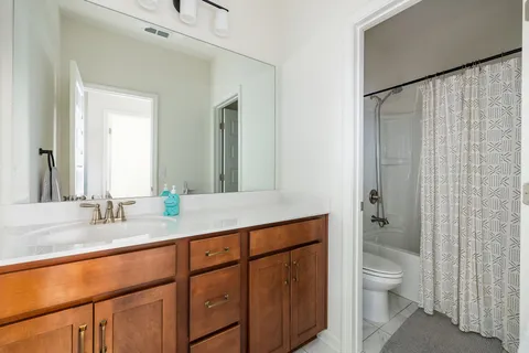a bathroom with a granite countertop sink toilet a shower and a large mirror