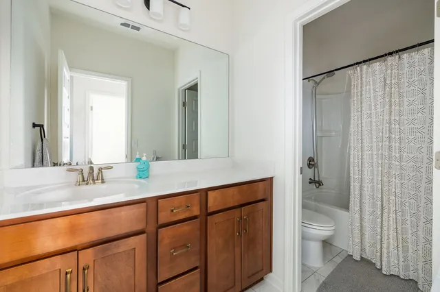 a bathroom with a granite countertop sink toilet a shower and a large mirror