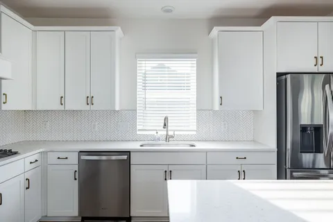 a kitchen with cabinets appliances a sink and a window