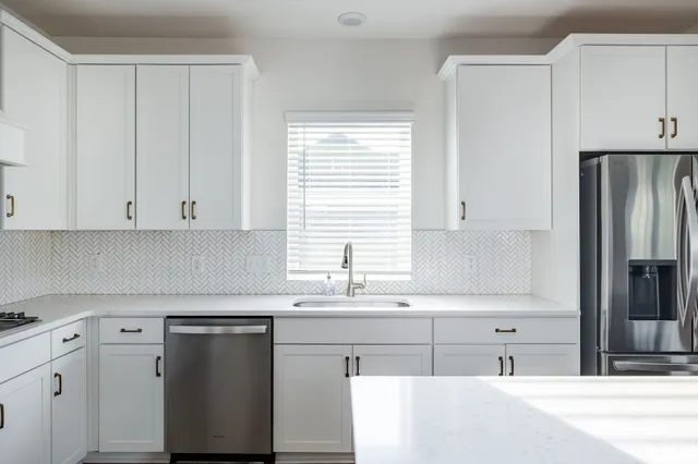 a kitchen with cabinets appliances a sink and a window