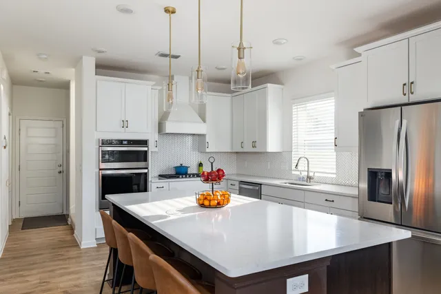 a kitchen with stainless steel appliances a stove a sink a refrigerator a center island and cabinets