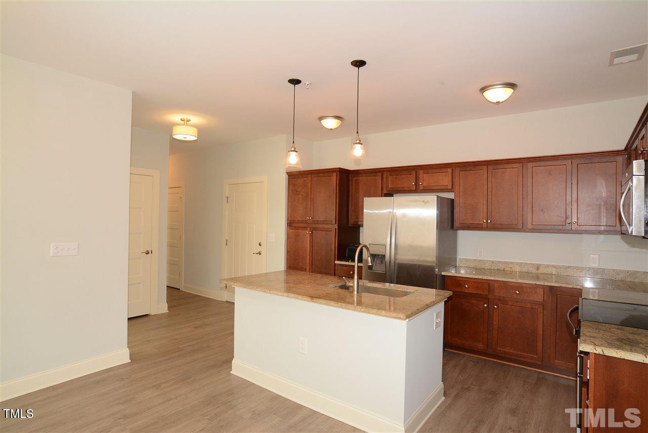 4031 Blackstone Drive, Unit 200 Raleigh, NC 27616 - Photo 4 of 6 a kitchen with kitchen island a sink stainless steel appliances and cabinets