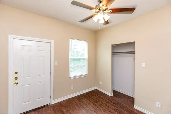 an empty room with wooden floor closet and windows