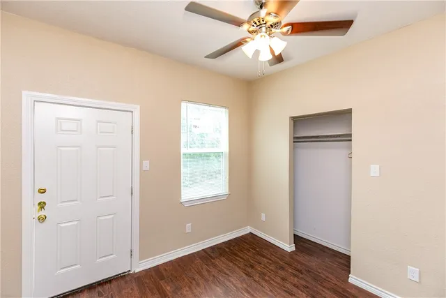 an empty room with wooden floor closet and windows