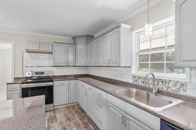 a kitchen with granite countertop a sink and white cabinets