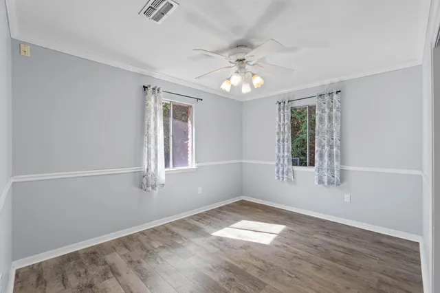 an empty room with wooden floor and windows