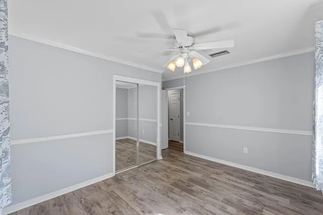 an empty room with wooden floor closet and ceiling fan