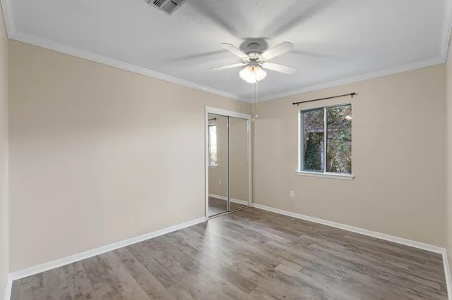 an empty room with wooden floor closet and fan