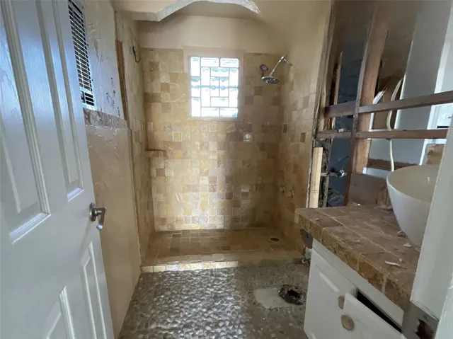 a bathroom with a granite countertop sink a toilet a shower and a window