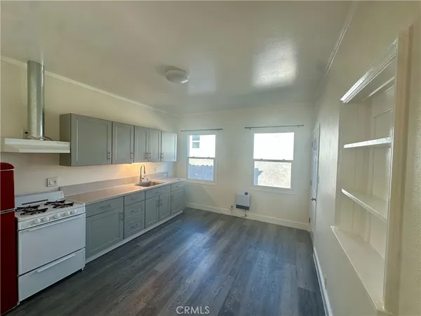 a kitchen with a wooden floor and white stainless steel appliances