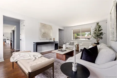 a living room with furniture two window and wooden floor