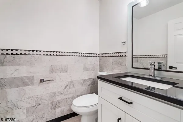 a bathroom with a granite countertop sink a toilet a mirror and shower