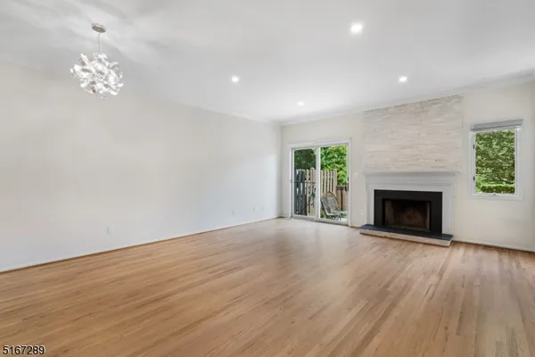 a view of an empty room with wooden floor fireplace and a window