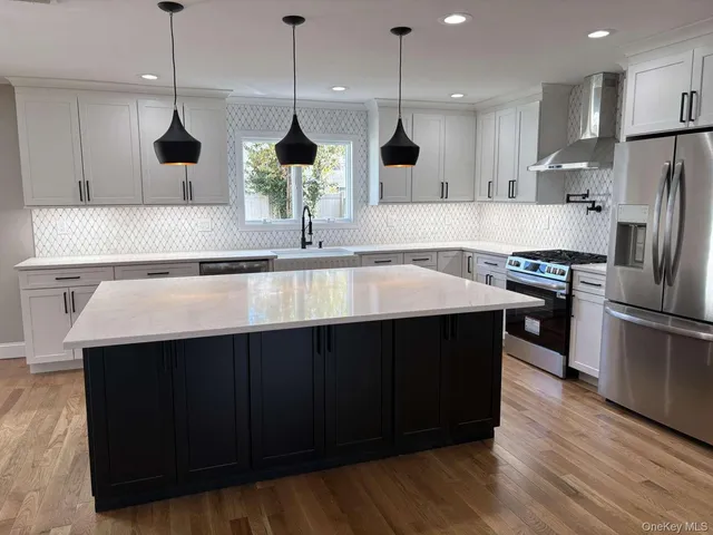 a kitchen with stainless steel appliances a sink a wooden floor and a kitchen island