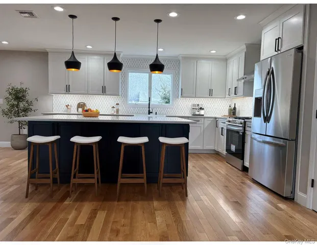 a kitchen with stainless steel appliances granite countertop a table chairs stove and refrigerator