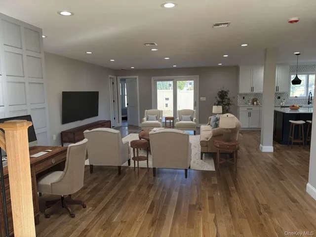 a living room with furniture a flat screen tv and kitchen view