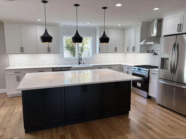 a kitchen with stainless steel appliances a sink a wooden floor and a kitchen island