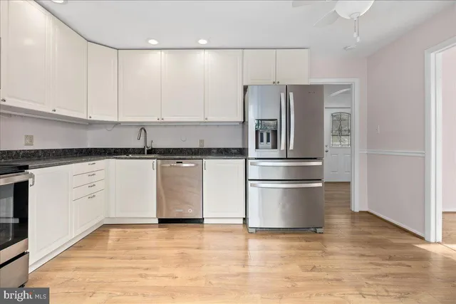 a kitchen with granite countertop a refrigerator and a stove top oven