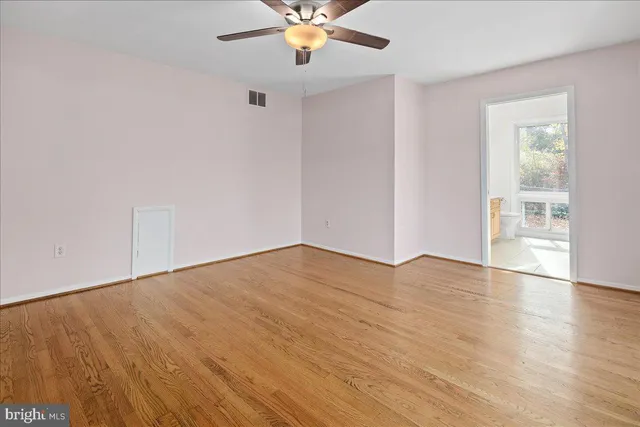 an empty room with wooden floor chandelier fan and windows