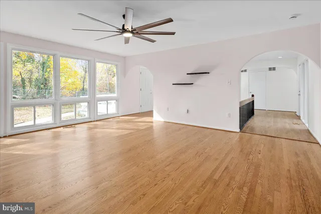 an empty room with wooden floor and windows