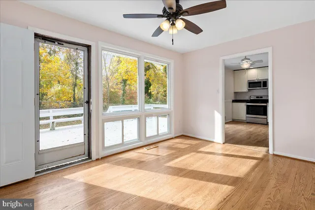 a view of an empty room with a window and wooden floor