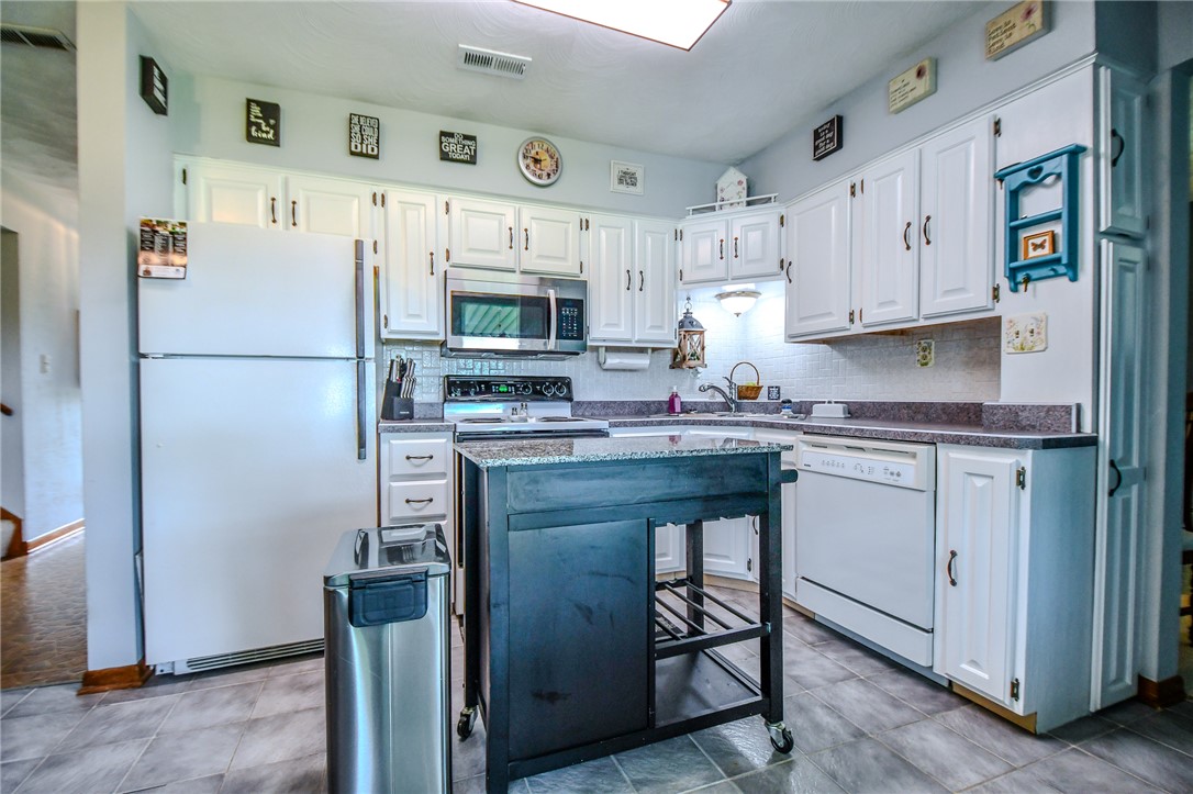 10833 Kendig Road Medway, OH 45341 - Photo 17 of 46 This bright kitchen features white cabinetry and modern appliances, offering a functional space for culinary endeavors.
