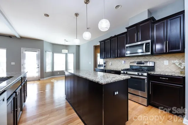 a kitchen with stainless steel appliances granite countertop wooden cabinets a stove top oven a sink and dishwasher